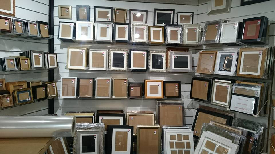 Picture frames in plastic wrapping on display shelves and the floor
