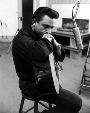 Black and white photo of Johnny Cash leaning on a guitar