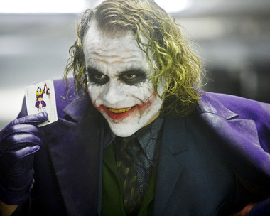 Heath Ledger as the Joker holding up a joker playing card